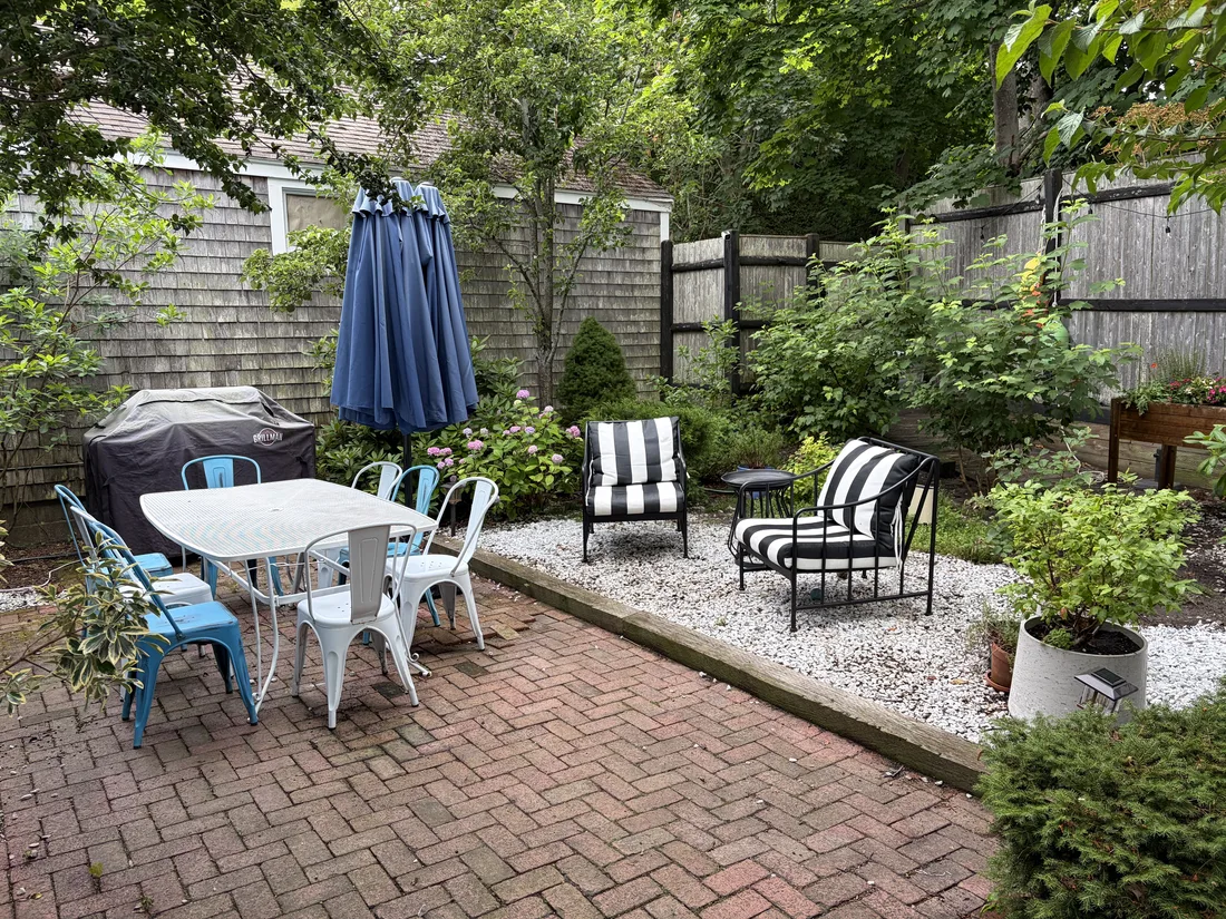 Private Provincetown garden with brick patio, dining table and lounge chairs