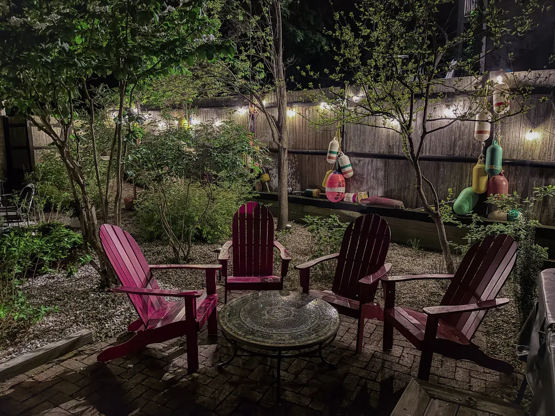 Private Ptown Perch garden illuminated at night with four Adirondack chairs